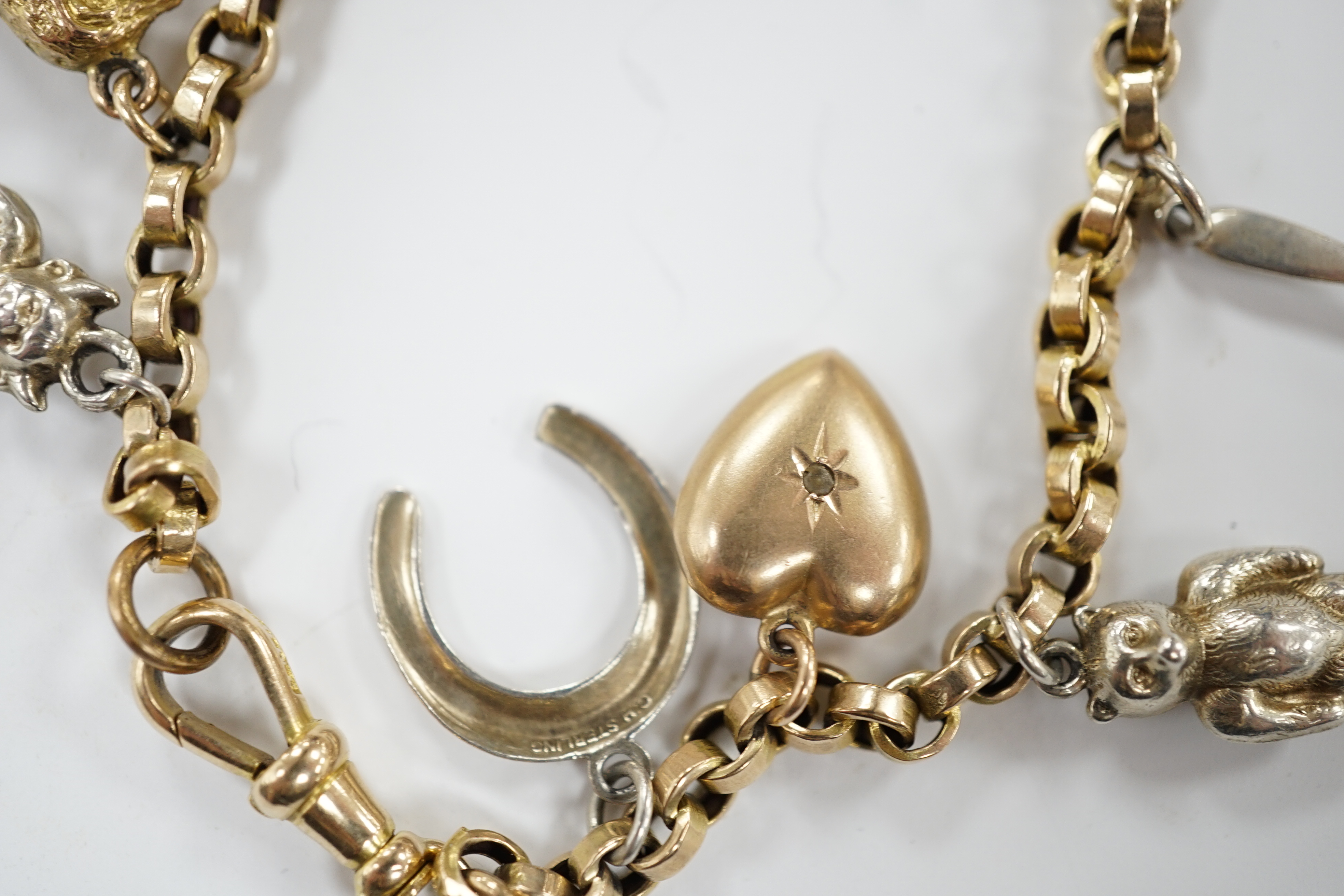A 9ct charm bracelet, hung with nine assorted yellow and white metal charms including sterling and 10k, 16cm
